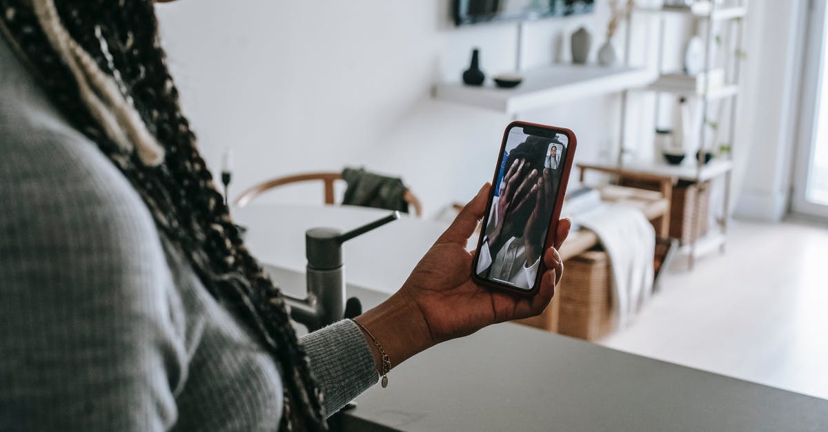 In Taiwan, what do you call those covered walkways? - Crop unrecognizable African American lady with long braids having video call on mobile phone with upset boyfriend covering face with hands while standing in modern kitchen