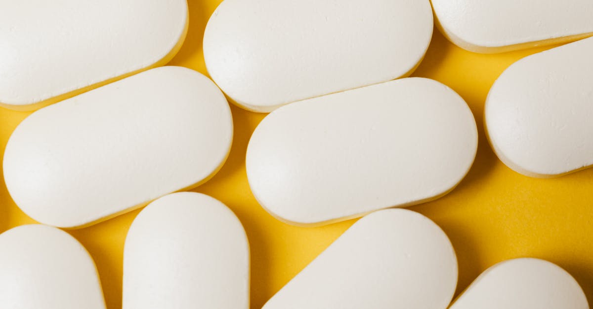 In transit with controlled medication - From above closeup of white ellipse shaped medical pills placed on bright yellow surface