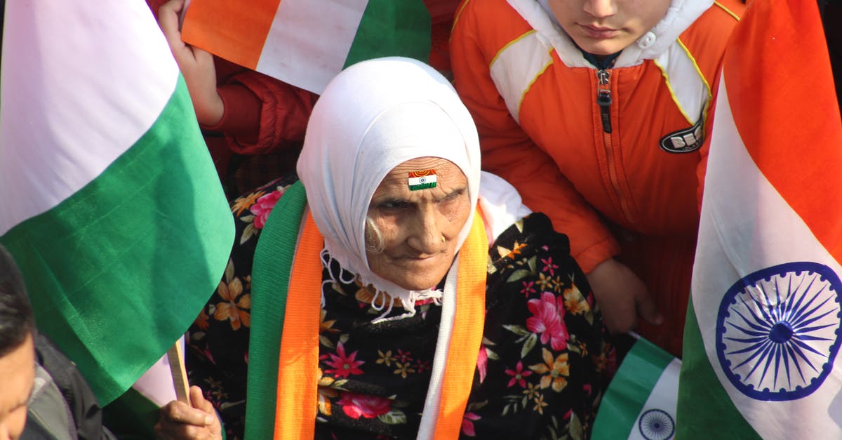 India visa expiring 2 days after arrival - An Elderly Woman Sitting With A Group of People While Holding A Flag