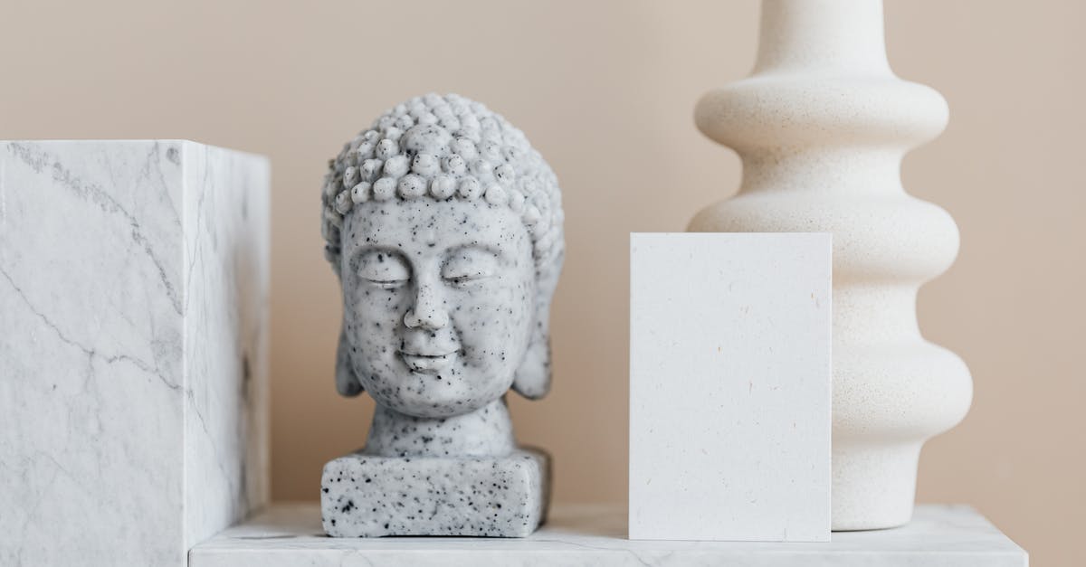 Indian Citizen/Canadian Permanent Resident never gets TSA Pre despite Nexus card - Granite bust of Buddha placed near white ceramic vase of creative geometric shape and blank card on white marble shelf against beige wall