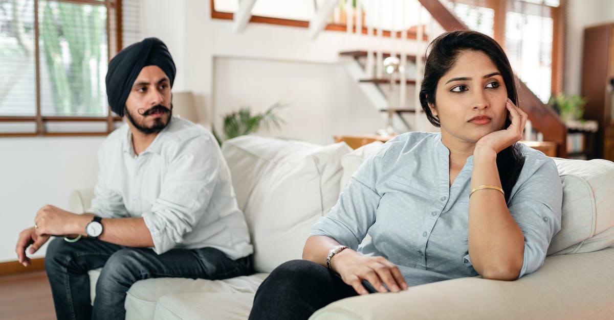 Indian eBusiness visa issues - Upset young Indian couple having argument while sitting on couch