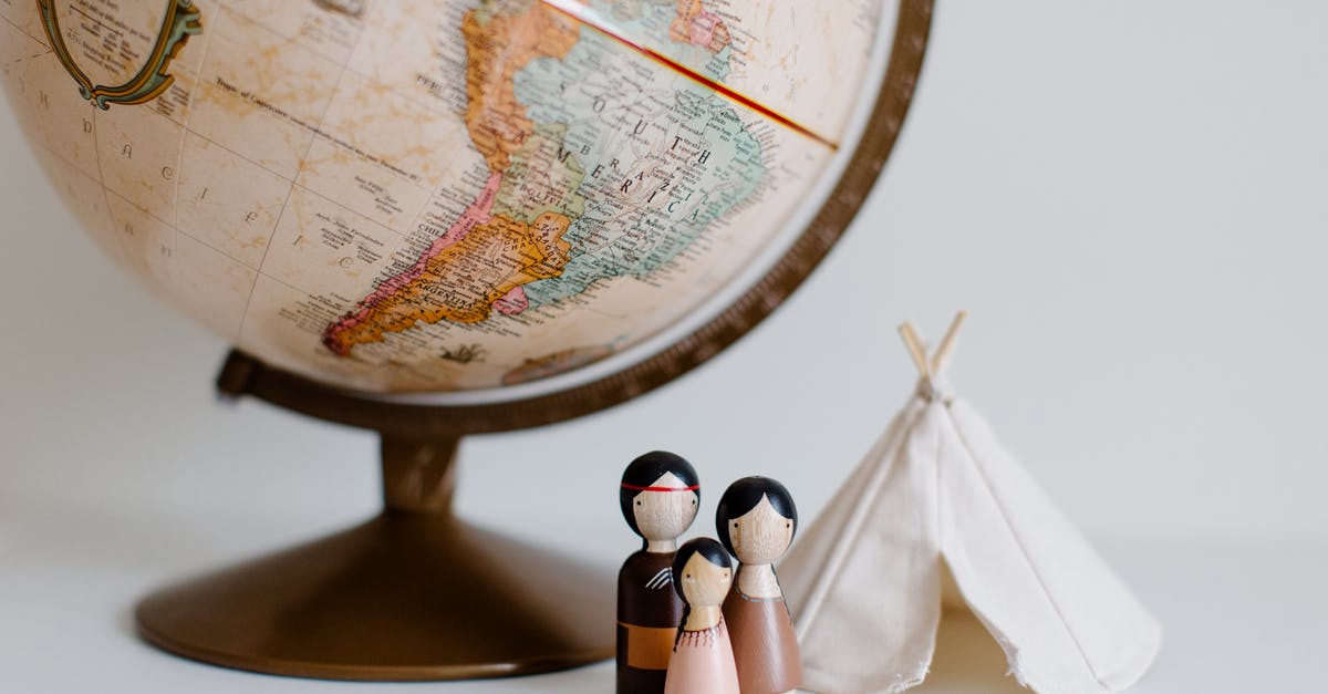 Indian leaving from nepal with a cancelled entry stamp - From above of miniature toys tipi house and American Indian family placed near vintage globe against gray background at daytime