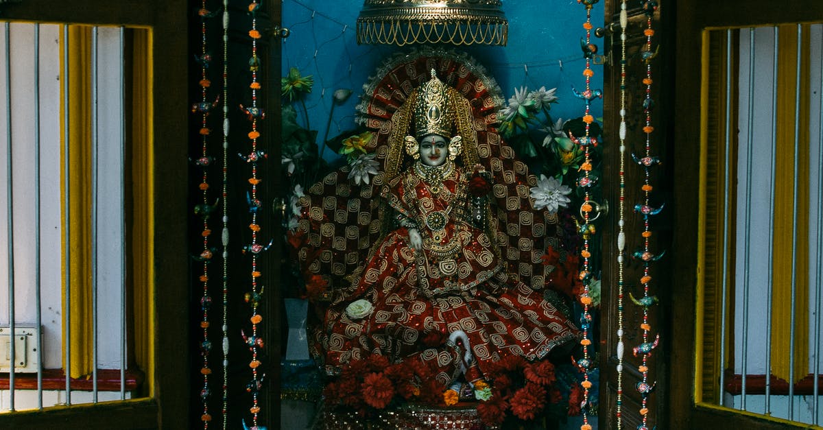 Indian National travelling to Dublin with a UK Visa - Colourful statue of Indian traditional god sculpture on throne with bright clothes decorated with flowers in traditional oriental altar for home prays and meditations