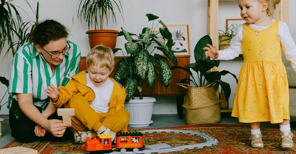 indian railway child issue [duplicate] - Mom and adorable little brother and sister in casual wear gathering in cozy living room during weekend and having fun together while playing with plastic railway