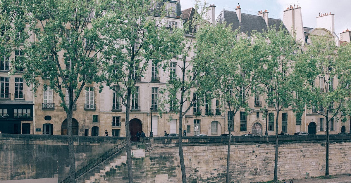 Indian traveling to Thailand with residence in Europe - Narrow walkway with green trees between river and city street with old high buildings