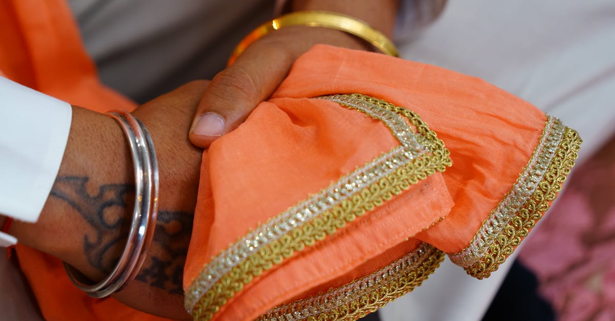 Indian visa with Bangladeshi origins - Crop unrecognizable Indian groom wearing traditional white wedding clothes and pink scarf with embroidery sitting with hands clasped