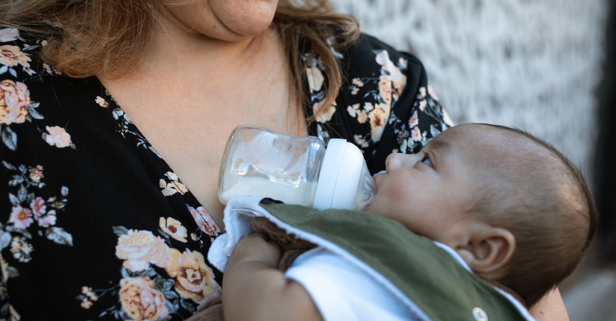 Infant boarding - A Woman in Floral Shirt Carrying a Baby while Drinking Milk