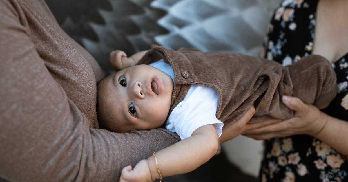 Infant boarding - A Baby Boy in Brown Jumper Lying Down on Two Persons Hands