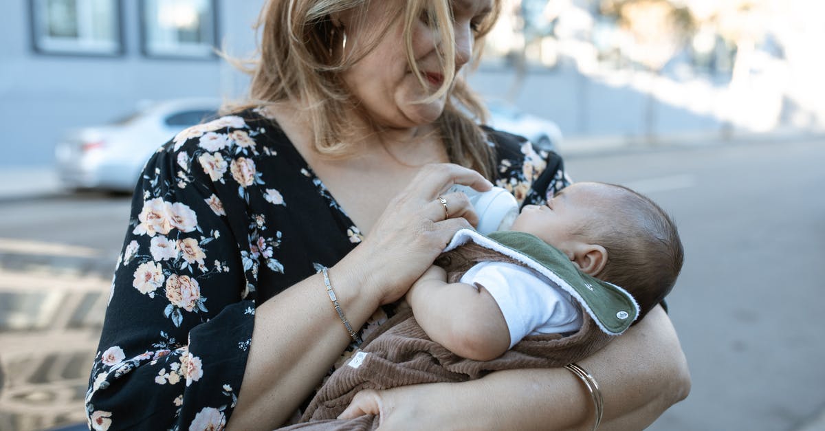 Infant visitor visa - A Mother Carrying Her Baby while Feeding Using a Milk Bottle