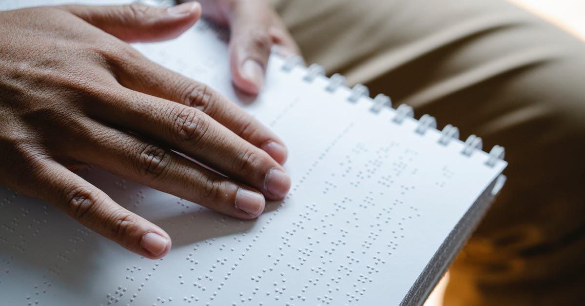 Information on people arriving from America [closed] - Closeup of crop unrecognizable blind person touching page with braille text while reading special book