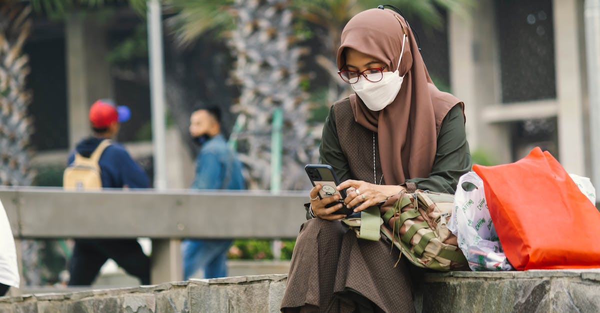 Inspection of over-packed bags - Woman in Brown Hijab and Face Mask Using a Cellphone