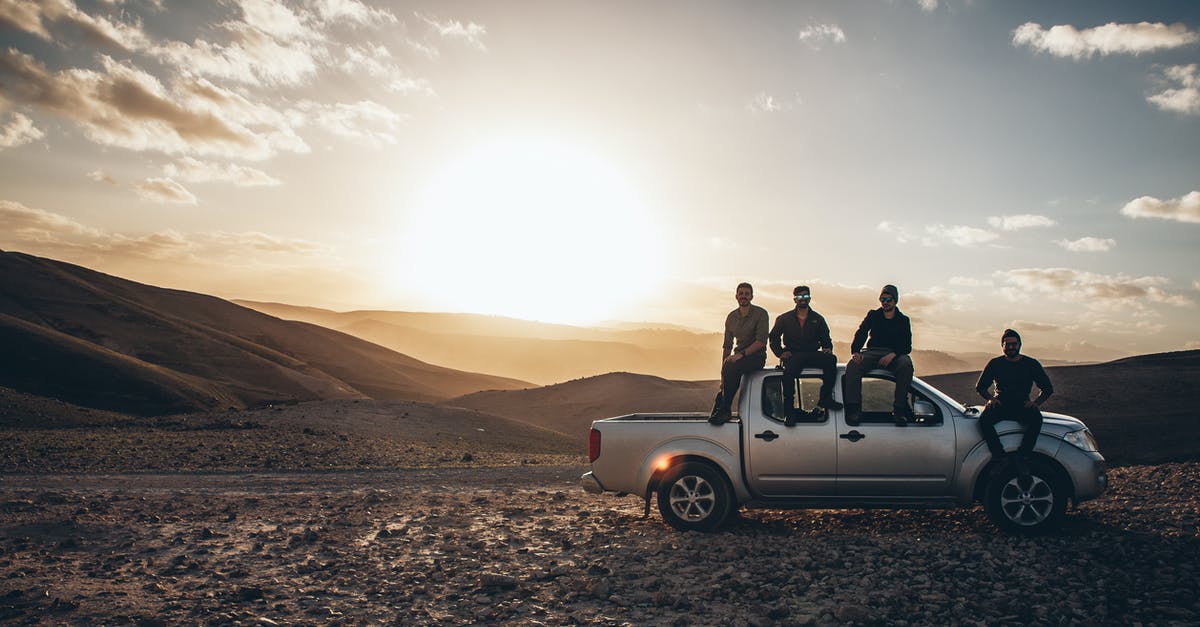 Insurance claim for cancelled trip due to sickness - Men Sitting on a Pickup Truck on a Road in Mountains 