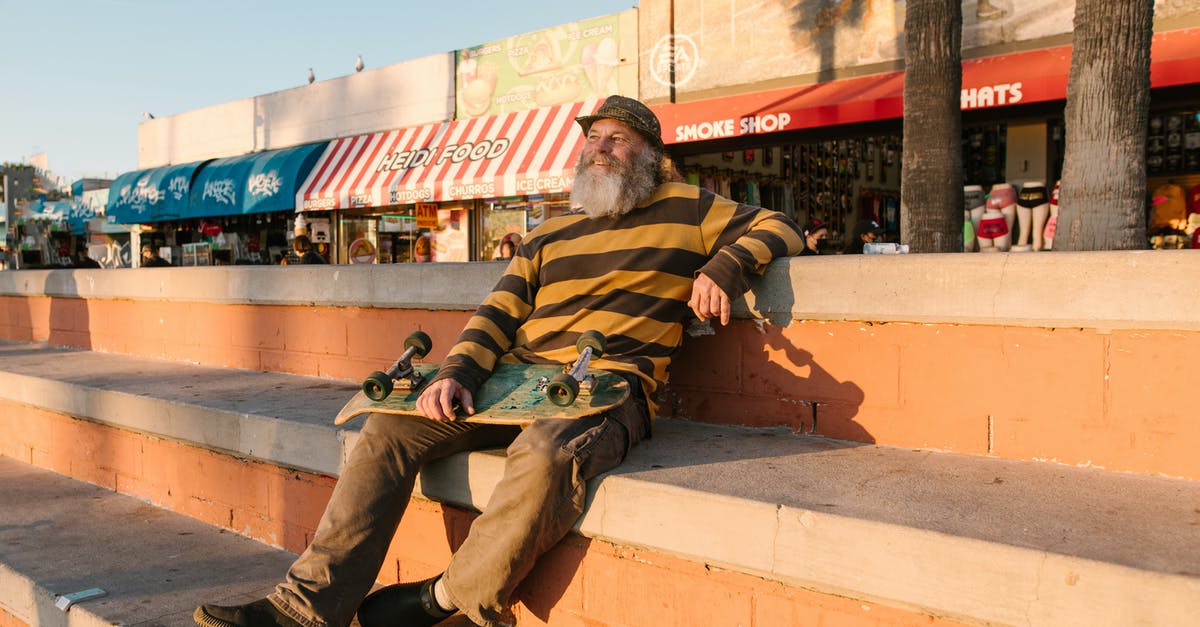 Intercity transportation in Cuba - Man in Green and Brown Stripe Long Sleeve Shirt Sitting on Brown Concrete Bench