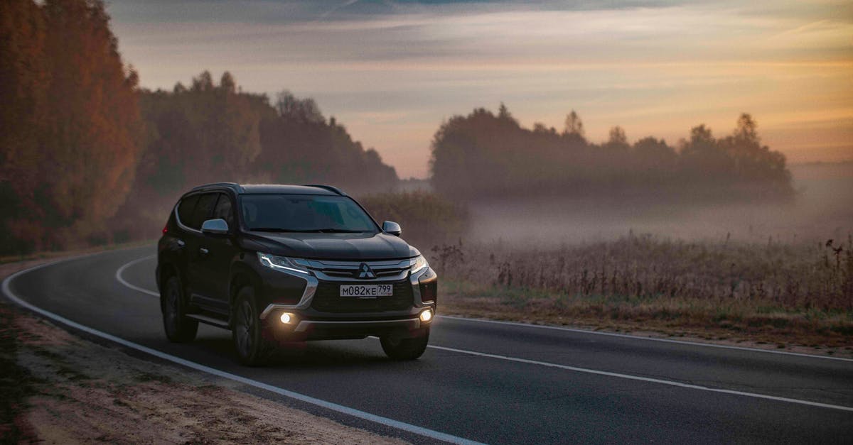 Inter-country one-way car rental in Europe? - Contemporary black offroader car driving along asphalt road in peaceful foggy countryside area in dusk