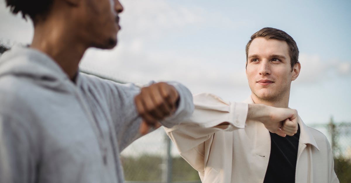 Is 'wai' greeting a serious thing? Is it inappropriate to 'over-wai'? - Serious multiethnic male friends doing elbow bump for protection and avoiding spreading of coronavirus infection and looking at each other