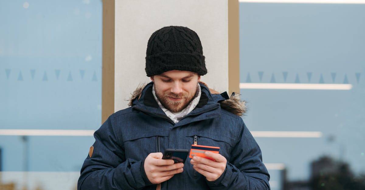 Is a credit card "proof of sufficient funds" to enter Ukraine? - Cheerful man entering details of credit card on smartphone on street