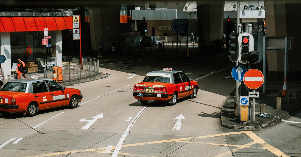 Is a day trip from Naha City to Taketomi Island possible? - From above of red taxi cars driving on asphalt street near crossroad in modern city district on sunny day