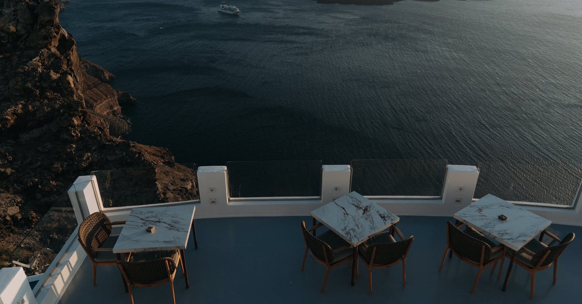 Is a visa required for Qeshm island in Iran? - White Wooden Table With Chairs on Brown Rock Formation Near Body of Water