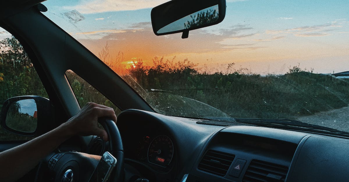 Is all of Afghanistan dangerous for travellers? - Crop unrecognizable person browsing mobile phone and driving car along rural gravel road in sunset time