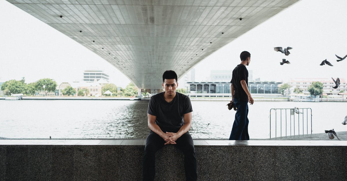 Is appearance important at the border? - Asian man sitting on embankment under bridge