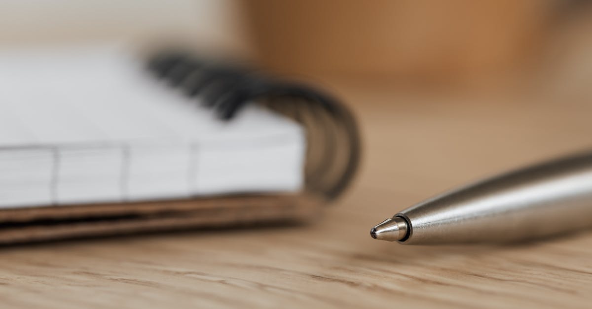 Is Canadian TRV open to visit visas at this point? - Side view closeup of opened ring bound notebook with blank pages near silver ball point pen placed on wooden table