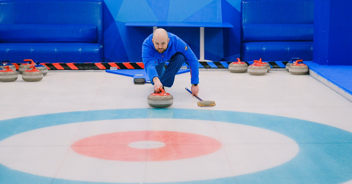 Is complimentary Wi-Fi available on ICE trains outside of Germany? - Focused male in blue activewear choosing tactic and throwing stone while playing curling on ice rink