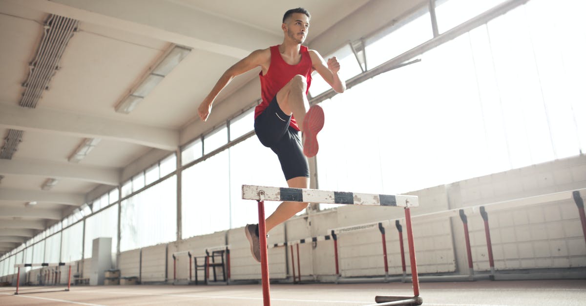 Is Fast Track Security in Heathrow included with business class tickets? - Powerful male athlete jumping over hurdle on running track while training at sports hall