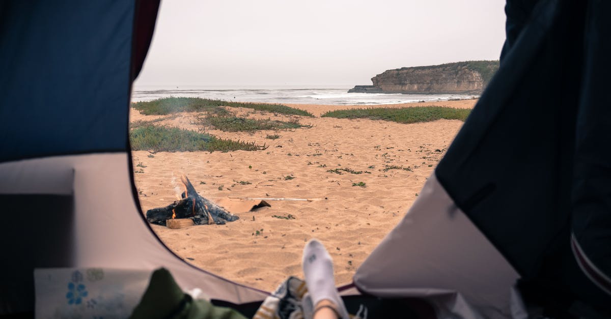 Is Guantánamo Bay, Cuba open to visitors/tourists? - Unrecognizable tourist resting in tent with opened door in nature on sandy seashore with rippling sea and rocky cliff in distance