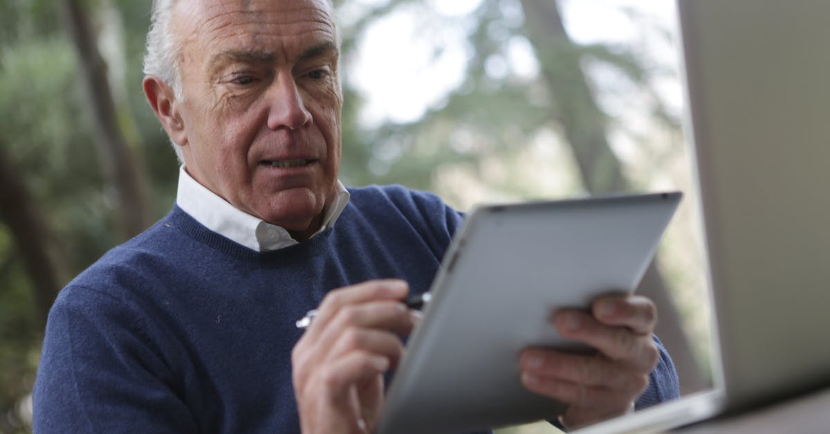 Is iPad counted as a second Laptop? [closed] - Man in Blue Sweater Holding Silver Ipad