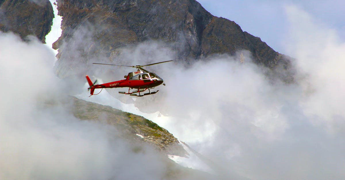 Is it better to travel by train or plane when there is risk of snow in the eastern US? - Red Helicopter on Top of Foggy Mountain
