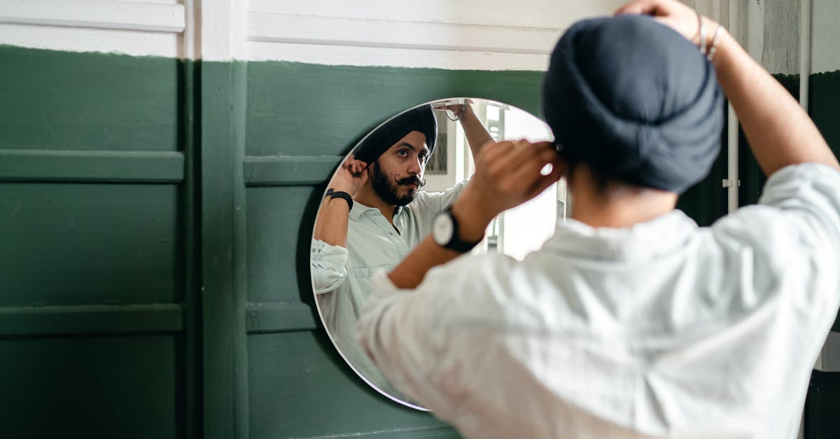 Is it considered uncouth to check in early into a hotel? - Young ethnic man looking of mirror at home