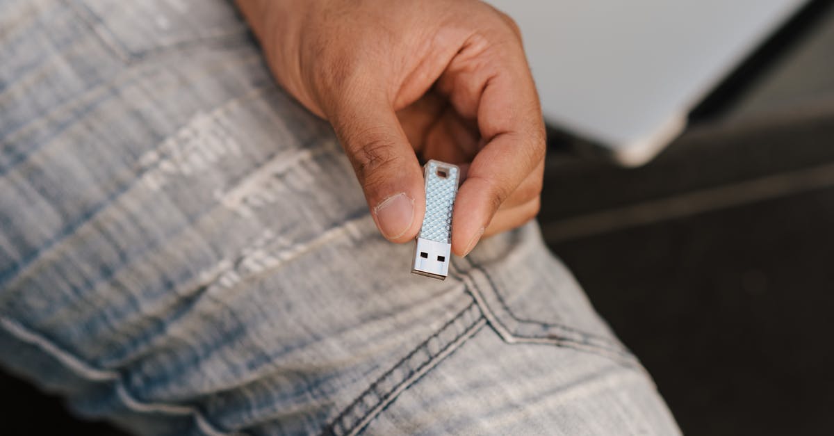 Is it ever useful to allow access to phone data when connecting one's phone to an airplane USB plug? - From above of crop anonymous male in jeans demonstrating flash drive while sitting near laptop