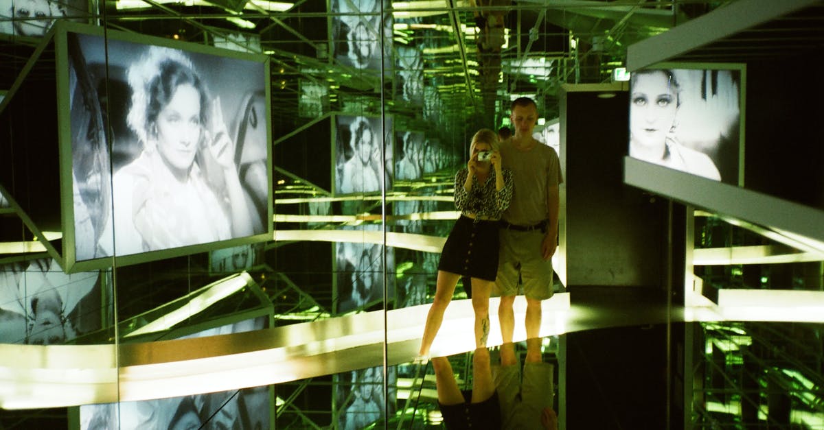 Is it legal to take photos at the airport? - Man and Woman Standing Near Photo of Woman Inside Glass Room