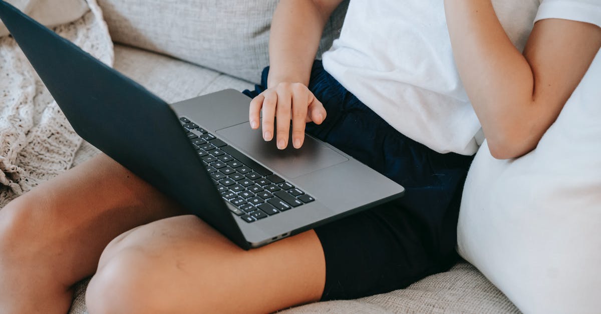 Is it more convenient to live in Brussels or in Leuven? [closed] - From above of crop unrecognizable self employed young lady in casual clothes sitting on comfortable couch and working online on laptop at home
