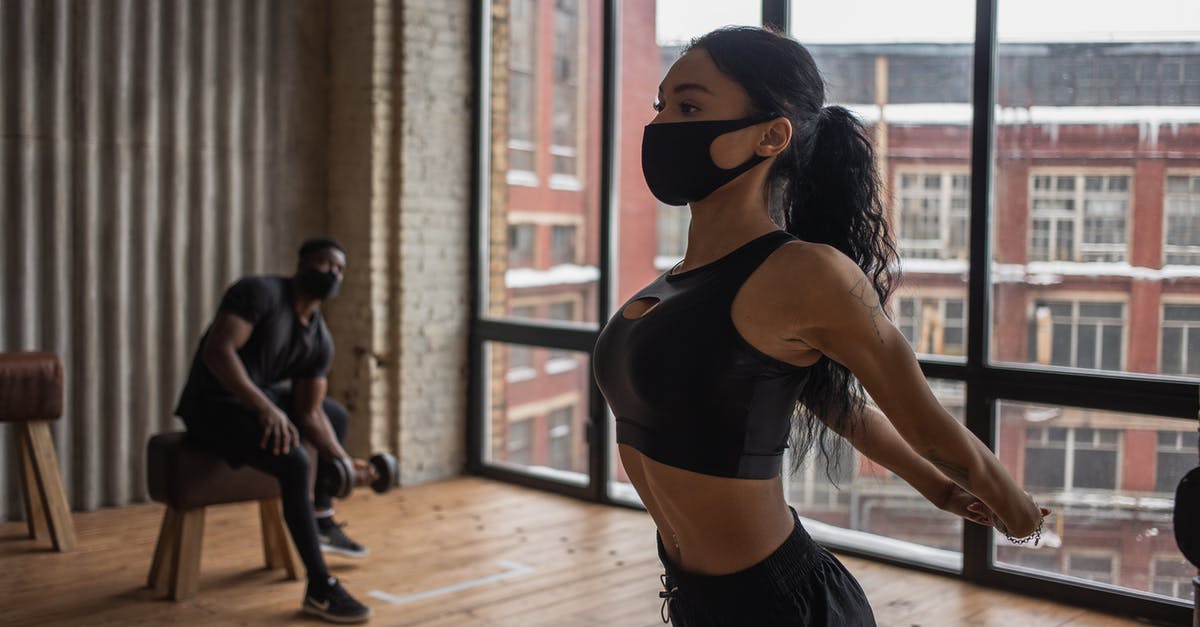 Is it normal practice to tip an Uber driver in London? - Fit African American sportswoman in mask stretching arms while training in gym during coronavirus pandemic with man lifting dumbbell