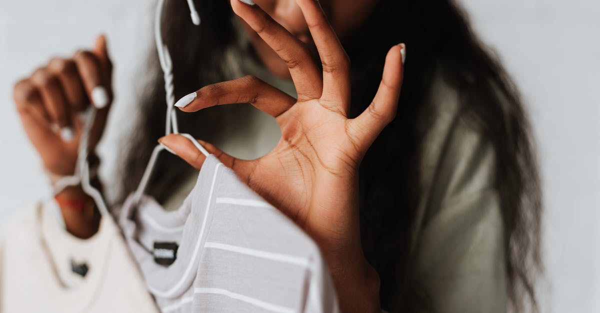 Is it okay to wear a pouch when flying? - Crop young African American female with wear on hangers demonstrating good gesture on light background