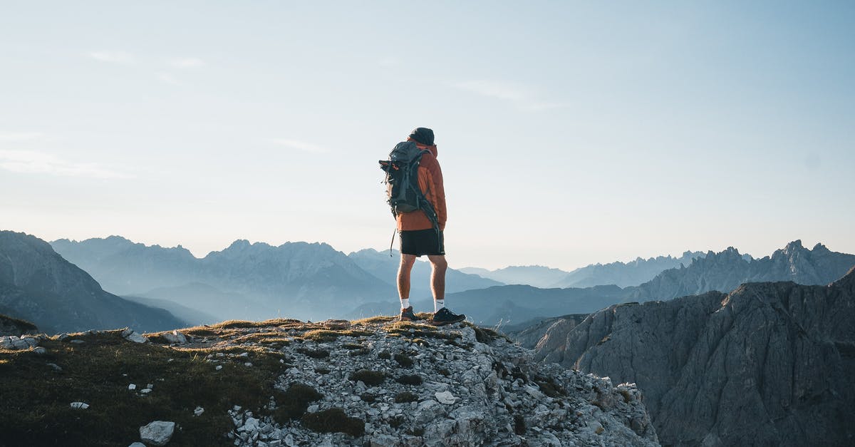 Is it possible to achieve 4G/LTE environment without buying local SIM? - Back view anonymous male explorer with backpack standing on rough mountain peak and enjoying breathtaking scenery of severe highland on clear day