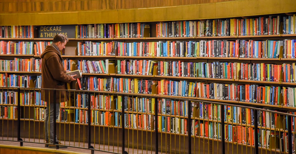 Is it possible to aggregate different hotel bookings in one search? - Side view of anonymous male standing near bookshelves with collection of colorful books in city library