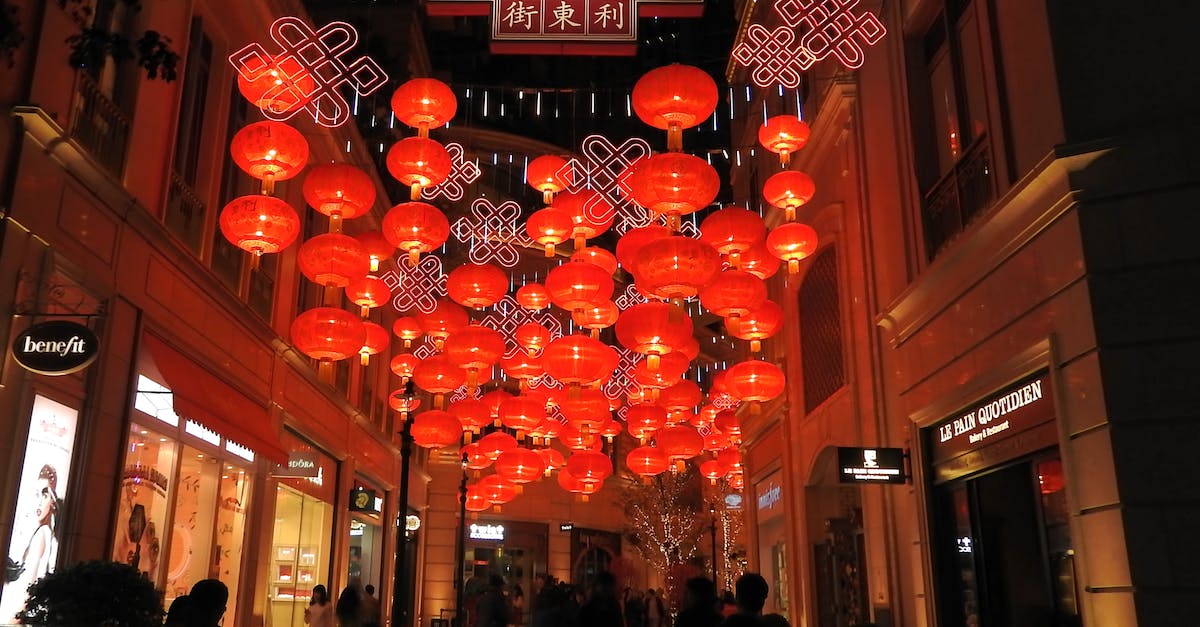 Is it possible to apply for a Chinese visa while travelling outside your home country? - Traditional Chinese lanterns hanging in street between buildings with people