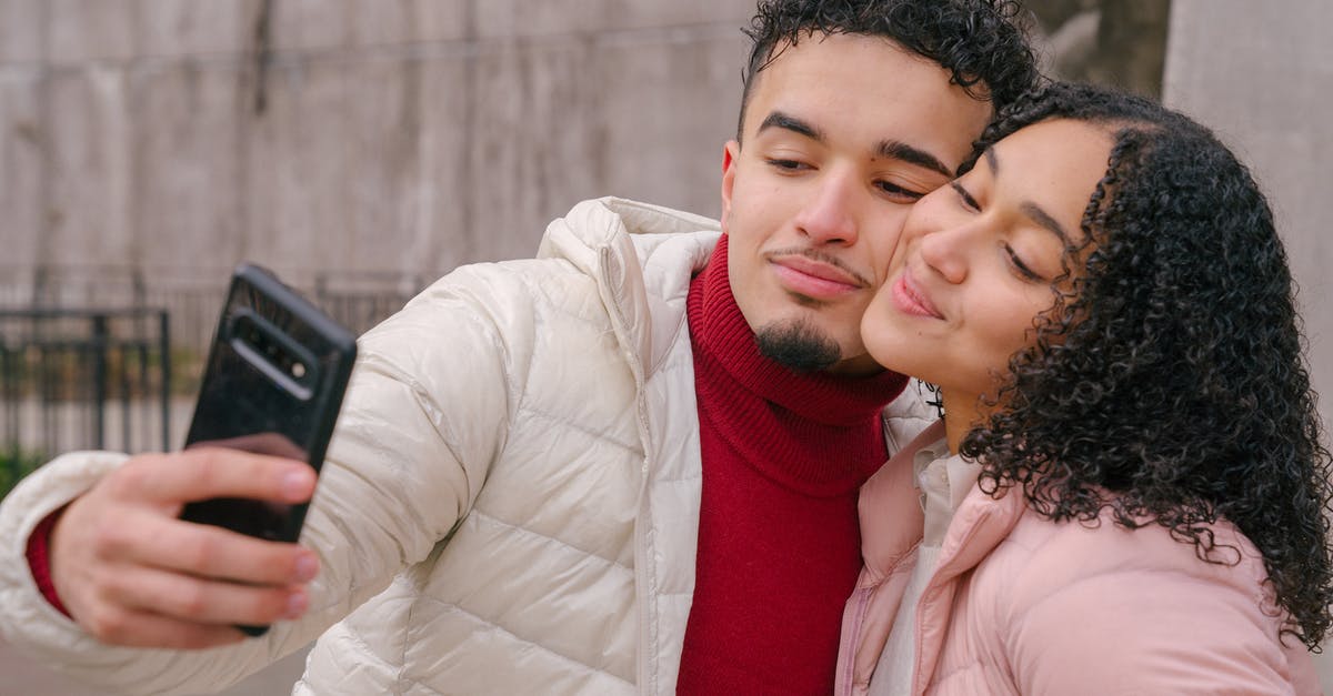 Is it possible to change date of a connection? - Enamored young Hispanic couple in warm casual clothes smiling and touching cheeks while taking selfie on mobile phone standing on street