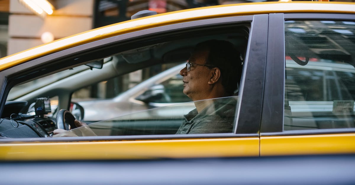Is it possible to go outside during my three-hour transit in Brussels? [duplicate] - Side view of ethnic male driver sitting behind steering wheel driving yellow cab with lowered window on city in street with blurred background