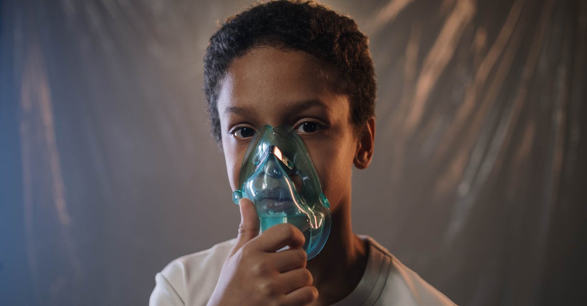 Is it possible to manually release an oxygen mask on airplanes? - A Boy in White Shirt Holding Green Oxygen Mask