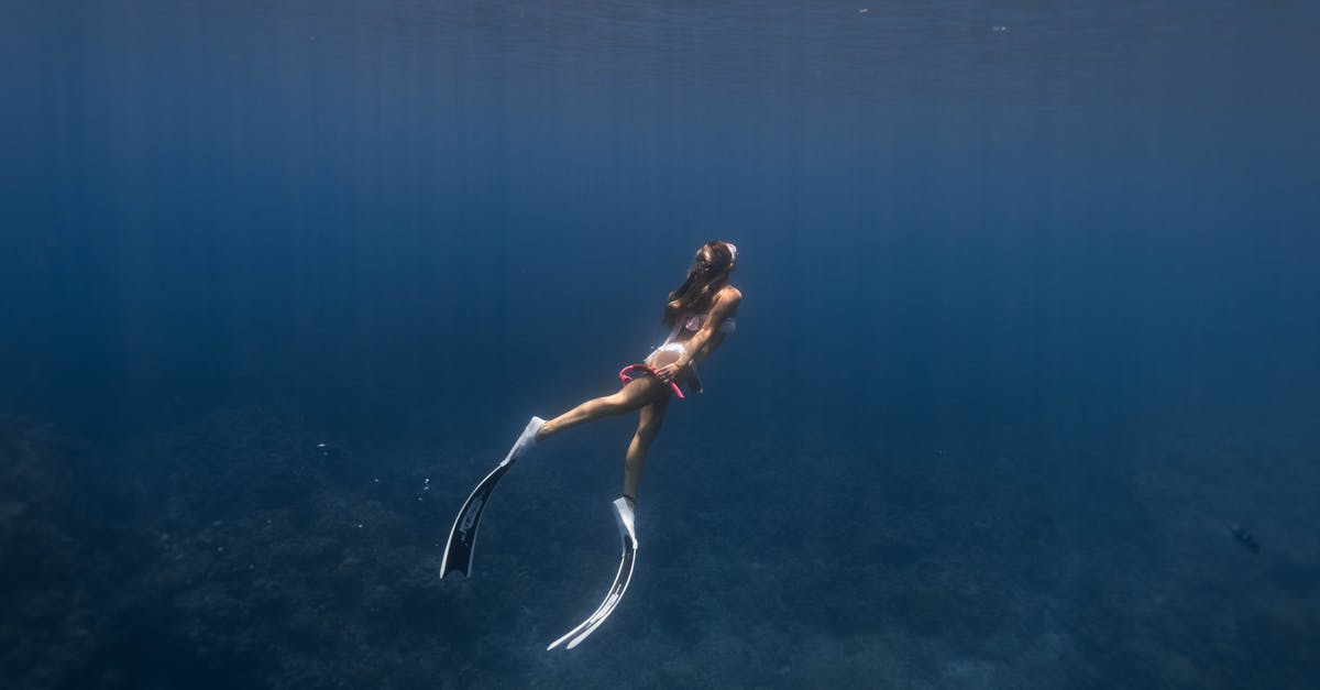 Is it possible to manually release an oxygen mask on airplanes? - Side view full body of anonymous sporty female diver in flippers and mask swimming underwater of blue sea near coral reefs