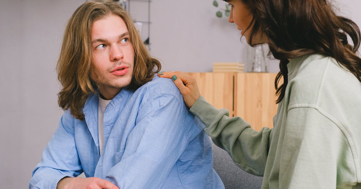 Is it possible to share an individual hotel room? - Concentrated woman talking and touching shoulder of pensive male in light room in daytime