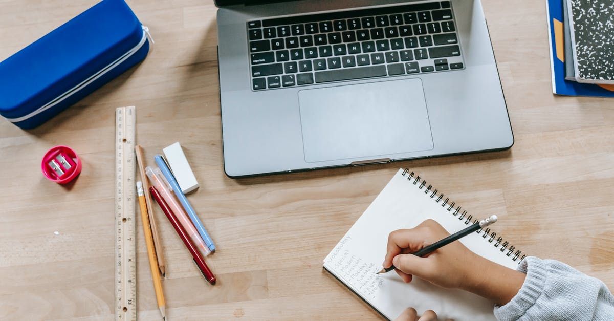 Is it possible to take a desktop PC as carry-on luggage? - Top view of crop anonymous smart pupil writing information in notepad while studying online with laptop at table with stationery