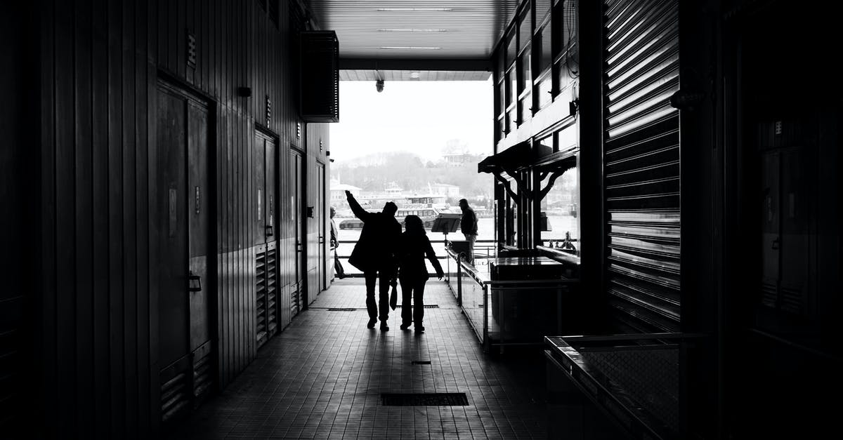 Is it possible to walk between Kowloon and Hong Kong Island? - Couple silhouettes walking on narrow passage of modern building