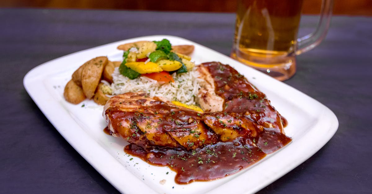 Is it rude to ask if the food contains pork or alcohol? - From above of tasty grilled pork steak with barbecue sauce served with salad and fried potato on table near mug of beer