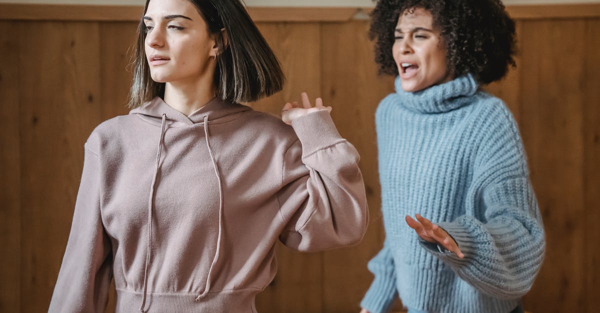 Is it rude to speak Swedish in Norway? - Mad African American female in warm sweater screaming at irritated female while having argument in light room with wooden walls