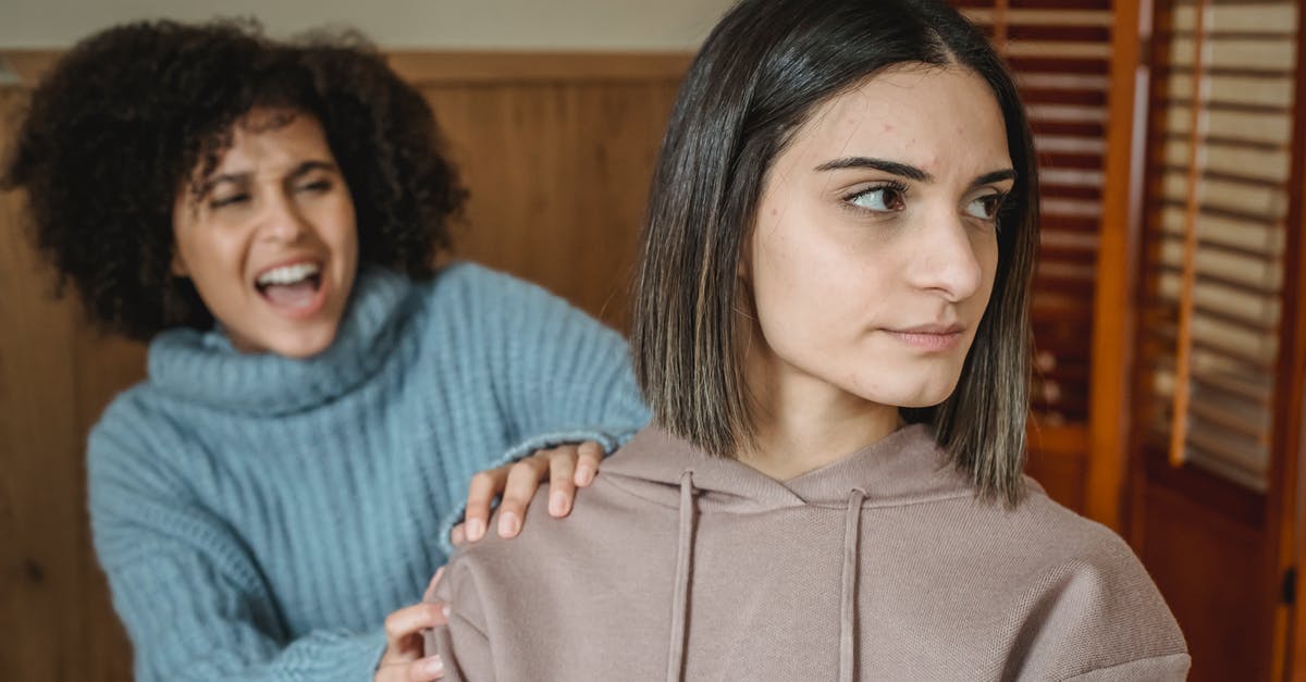 Is it rude to speak Swedish in Norway? - Angry African American female in casual wear screaming and grabbing shoulder of displeased female while having conflict in room at home