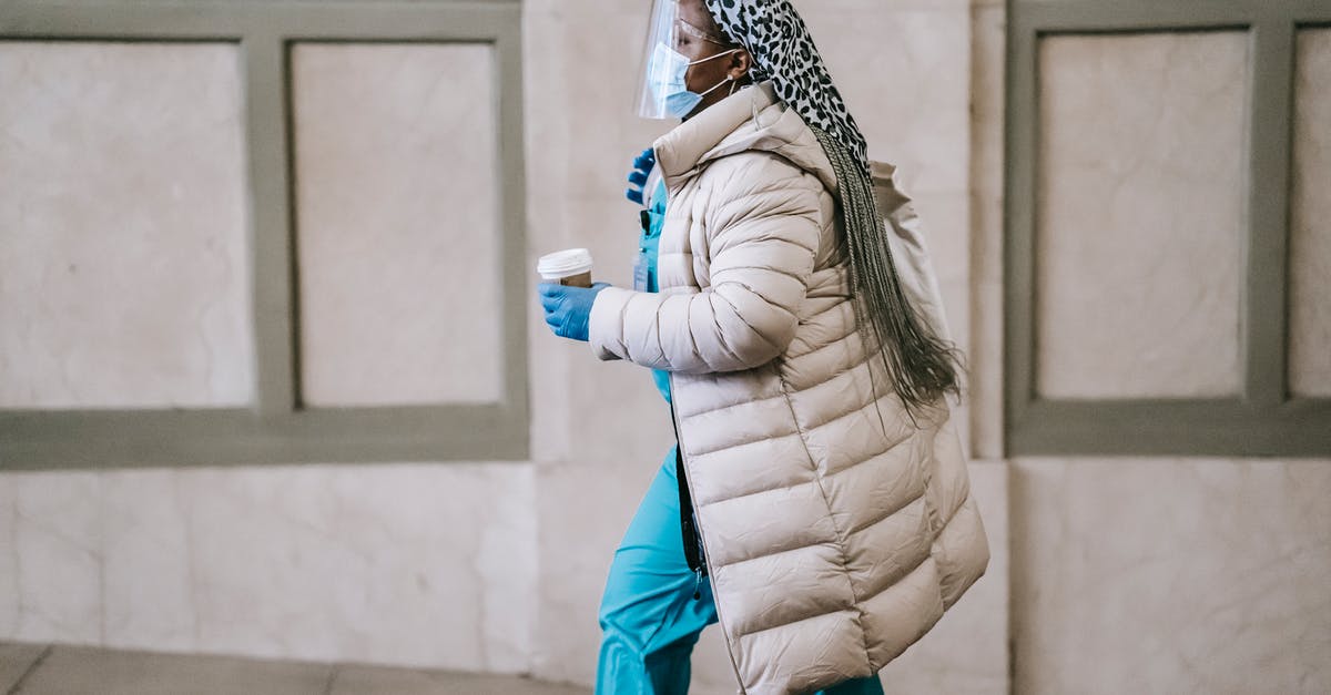 Is it safe to go to Içmeler, Turkey now? - Side view calm adult African American nurse in uniform and warm clothes wearing medical mask face shield and latex gloves walking with coffee to go on street